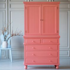 a pink armoire next to a blue chair