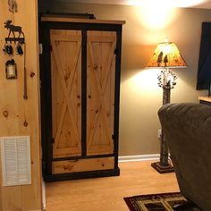 a living room with a couch, lamp and wooden cabinet in it's corner