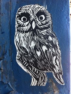 an owl painted on the side of a blue wall with peeling paint and black trim