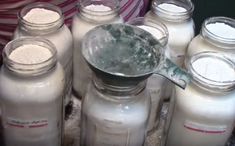 there are many jars with different types of milk in them and one is holding a measuring spoon