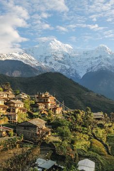 a mountain village with snow capped mountains in the background