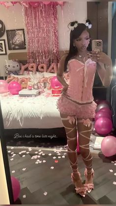 a woman taking a selfie in front of a mirror with balloons and streamers