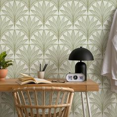 a table with a lamp, book and plant on it next to a wallpaper