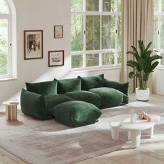 a living room filled with green couches and white tables in front of large windows