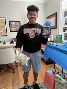 a young man standing in his living room holding up some kind of item that he is holding