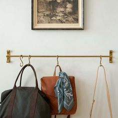 two purses are hanging on the wall next to a coat rack