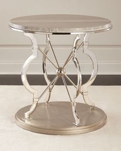 a round table with metal legs and a glass top on a white carpeted floor