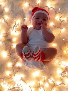 a baby is laying on the floor surrounded by christmas lights