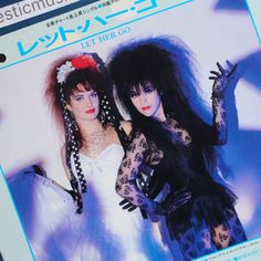 two women dressed in black and white posing for a magazine cover with their hands up