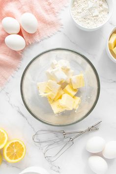 ingredients to make lemon cake laid out on a marble counter top, including eggs and butter