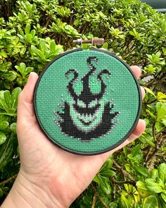 a hand holding up a green cross stitch pattern