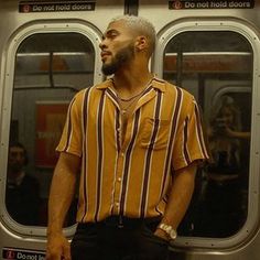 a man standing in front of a subway car with his hand on his hip and looking out the window