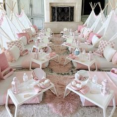 a room filled with lots of white and pink furniture in front of a fire place