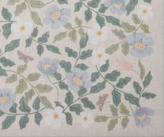 an embroidered fabric with blue flowers and green leaves