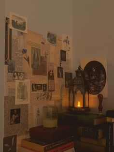 there is a candle on the table next to some books and pictures hanging on the wall