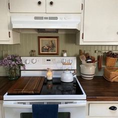 a white stove top oven sitting inside of a kitchen next to a wooden countertop