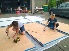 two women are working on some boards in the driveway