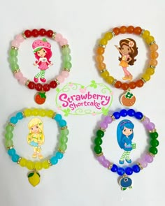 four bracelets with cartoon characters on them and the words strawberry shortcake written in large letters