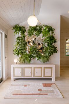 a living room with plants on the wall and a rug in front of an entryway