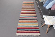 a multicolored striped rug on the floor next to a couch