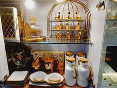 gold and white items are on display in a store window, including vases and dishes