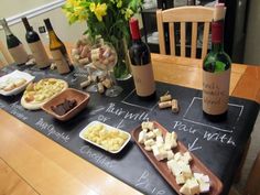 a table topped with lots of different types of food and wine bottles on top of it