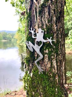 a metal frog sitting on the side of a tree