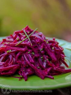 a green plate topped with red cabbage on top of a wooden table