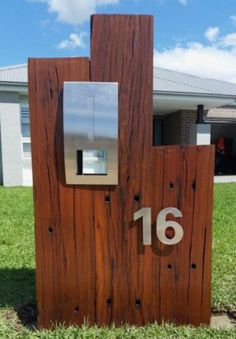 a mailbox made out of wood and metal with the number sixteen on it in front of a house