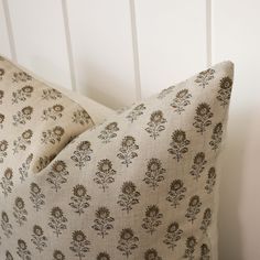 two pillows sitting next to each other on top of a wooden floor in front of a white wall