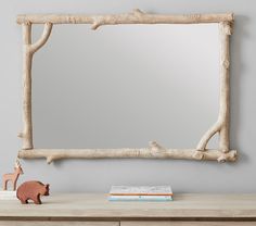 a wooden mirror sitting on top of a dresser next to a toy deer and tree branch