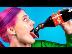 a woman with pink hair drinking from a coca cola bottle