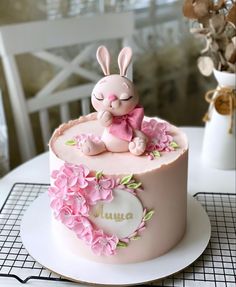 a cake decorated with pink flowers and a bunny figurine sitting on top of it