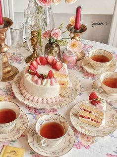 a table topped with plates and cups filled with cake next to teacups covered in strawberries