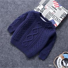 a blue knitted sweater next to a tag on a gray surface with a pair of scissors