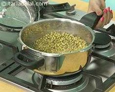 a woman is cooking food on the stove top with a large pot full of green beans