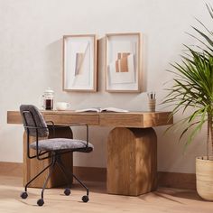 a chair sitting next to a wooden desk with two pictures on the wall behind it