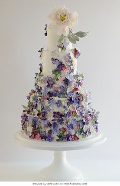 a multi - tiered wedding cake with flowers on the top is white and purple