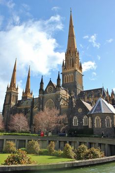 an old church with steeples and trees in the foreground