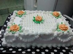 a cake with white frosting and orange flowers sitting on top of a polka dot table