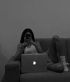 a woman sitting on a couch with her laptop and cell phone in front of her