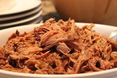 a white bowl filled with shredded meat on top of a table