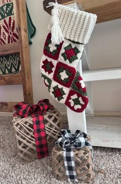 two knitted christmas stockings on top of each other next to a basket with a bow