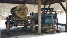 an old truck is parked under a wooden structure with logs on the front and back