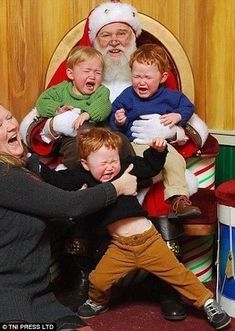 a woman kneeling down next to children in front of a drum set with santa clause on the wall behind her