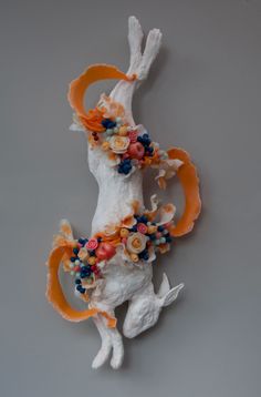 an animal sculpture with flowers on it's head and tail, made out of clay