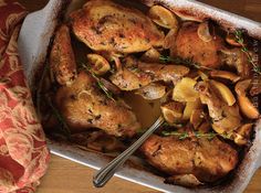 a pan filled with chicken and mushrooms on top of a wooden table