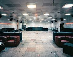 an empty room with couches, tables and lights on the ceiling is shown in this image