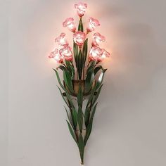 a wall mounted light with pink flowers on it's side and green leaves in the middle