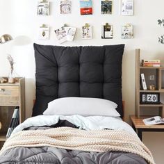 a bed with a black headboard and white sheets in a room filled with pictures on the wall